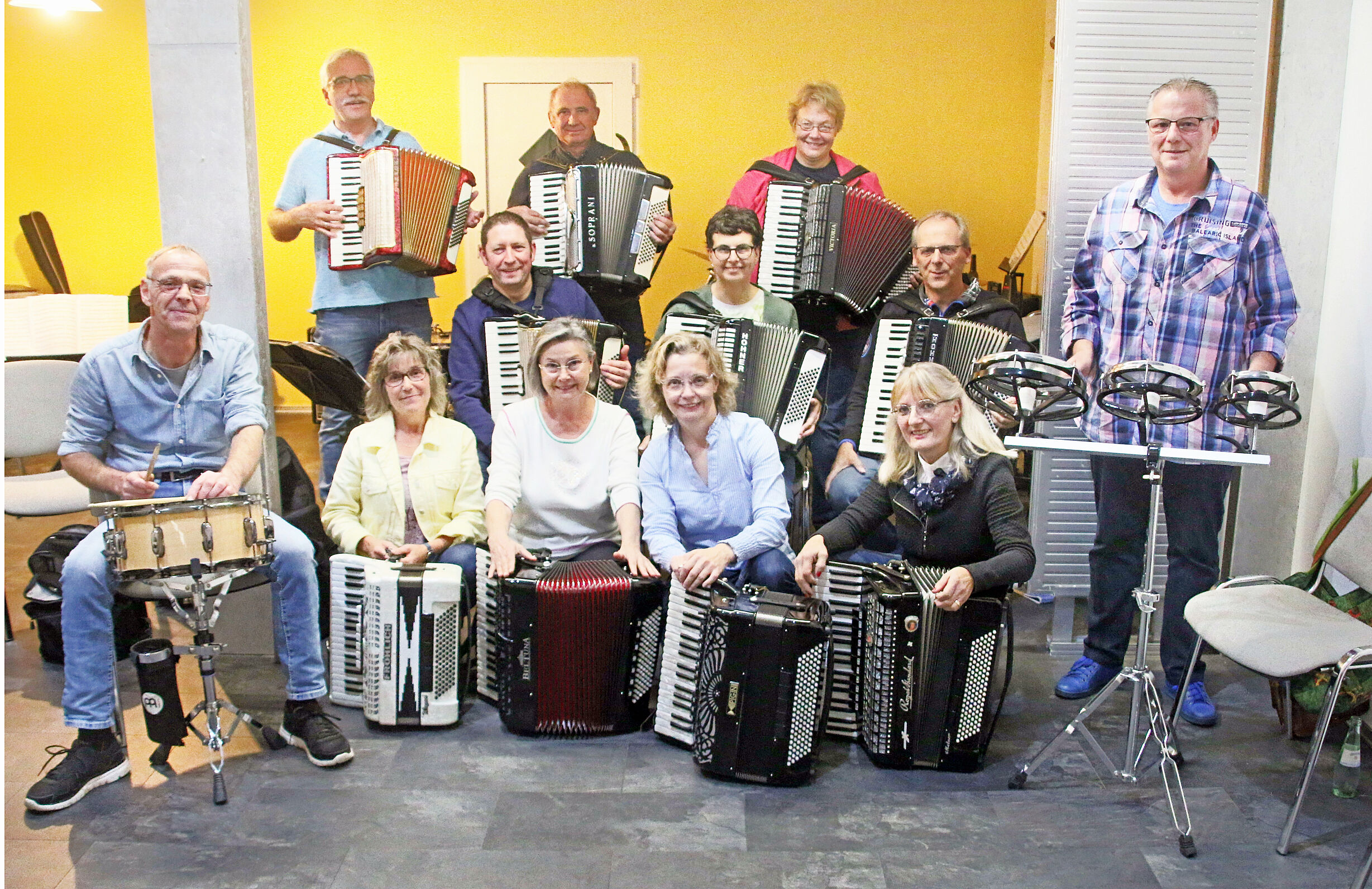 Menschen mit Akkordeons und Trommeln sitzen in einem Raum