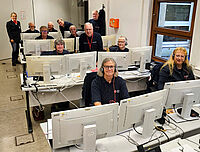 Mehrere Mitarbeiter vom DRK Soest sitzen vor Monitoren und tragen Headsets.