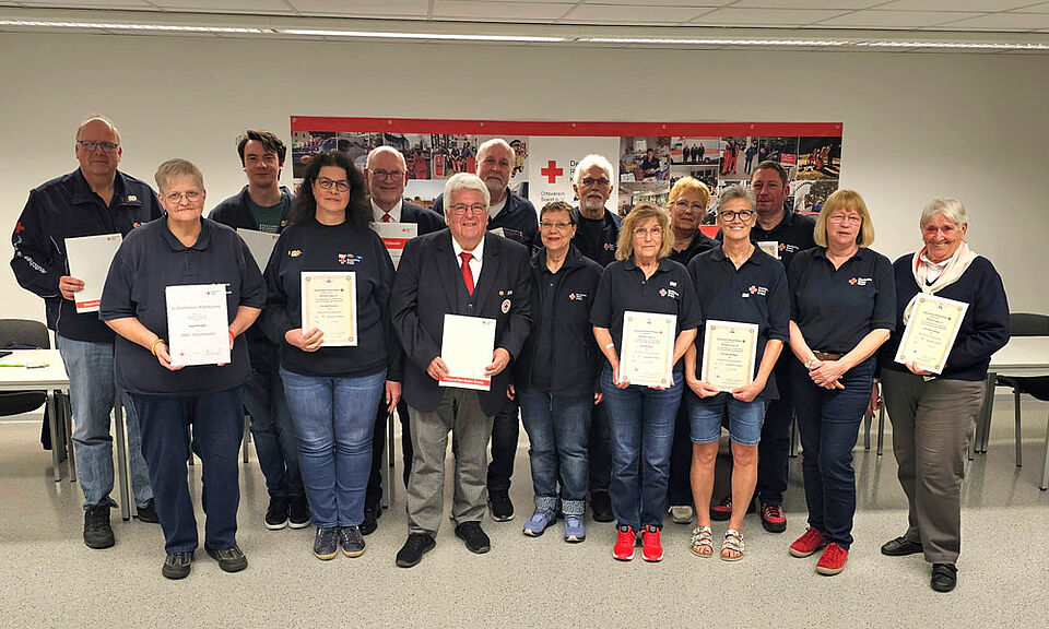 15 Personen stehen mit Ihren Urkunden in einer zweierreihe in einem beleuchteten Raum beim DRK Soest.